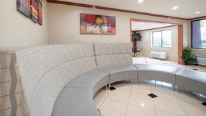 A curved grey sofa in a lobby with a large abstract painting, a window, and a radiator.