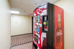 A vending machine with a Coca-Cola logo, a payment slot, and a beverage selection panel. - King Bed Non-Smoking (Houston)