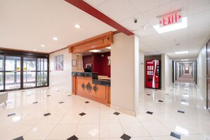 A hotel lobby with a reception desk, a Coca-Cola vending machine, and a red exit sign. - King Bed Non-Smoking (Houston)