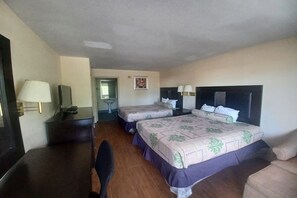 Quarto de hotel com duas camas, uma mesa de escritório com luminária, uma cadeira e uma mesa de cabeceira.