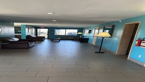 A spacious lobby with a tiled floor, seating area, and large windows.