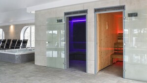 Un espace piscine intérieur moderne, doté d’un jacuzzi à jets et d’un sauna, le tout protégé par des parois de verre.