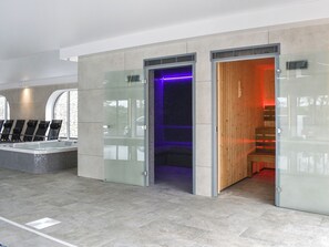 Ein moderner Poolbereich im Innenbereich mit einem gläsernen Whirlpool und einer Sauna.