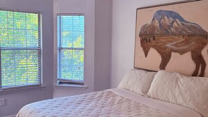 Un dormitorio con una cama, un ventilador de techo y una ventana con persianas.