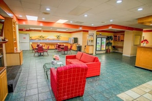 A hotel lobby with a red sofa, dining area, and a kitchen counter. - King Bed|Non-Smoking (Greensboro)