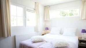 Un dormitorio con cama, dos mesitas de noche, una ventana y un radiador.