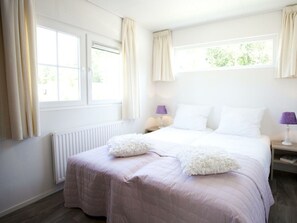 A bedroom with a bed, two nightstands, a window, and a radiator. - Holiday Home in Velsen-zuid With Terrace (Velsen-Zuid)