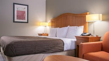 Habitación de hotel con una cama, dos lámparas de noche, un teléfono, una silla naranja y un cuadro en la pared.