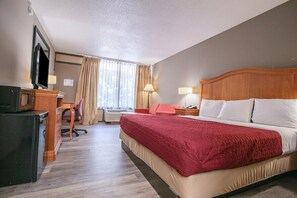 Ein Hotelzimmer mit Bett, Schreibtisch, Stuhl, Fernseher und Vorhängen.