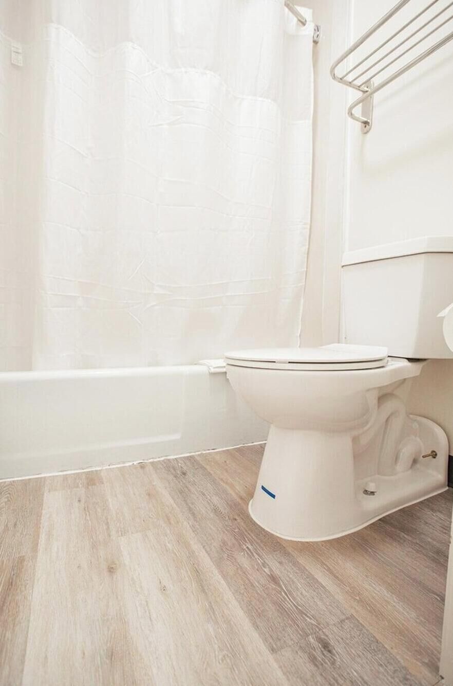 A bathroom with a toilet, a shower curtain, and a metal towel rack.