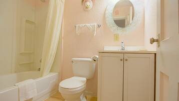 Ein Badezimmer mit Badewanne, Toilette, Waschbecken und Spiegel.