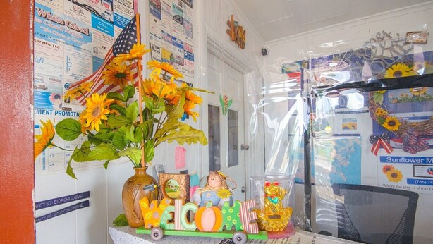 Een kamer met een welkomstbord, een vaas met zonnebloemen, een klein treintje als decoratie en een muur met verschillende posters.
