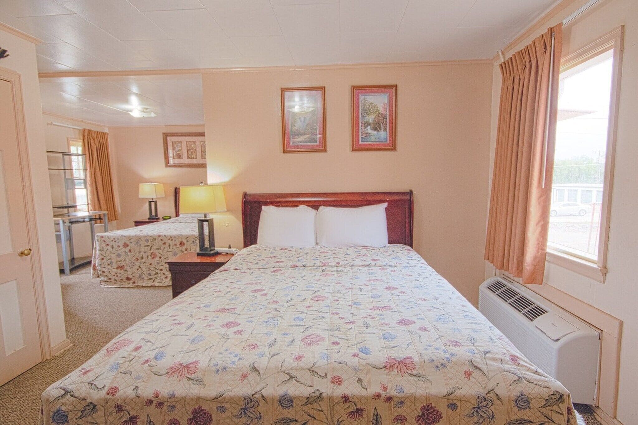 Una habitación de hotel con una cama grande, un escritorio, una silla, una lámpara y una ventana con cortinas.