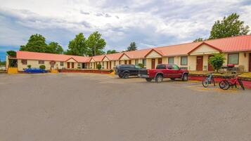 A motel with multiple rooms, a parking lot, and a few parked vehicles.