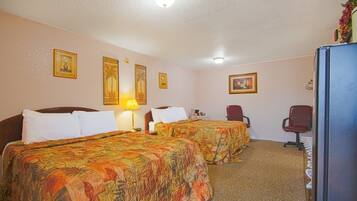 A hotel room with two beds, a desk, a chair, and a refrigerator.