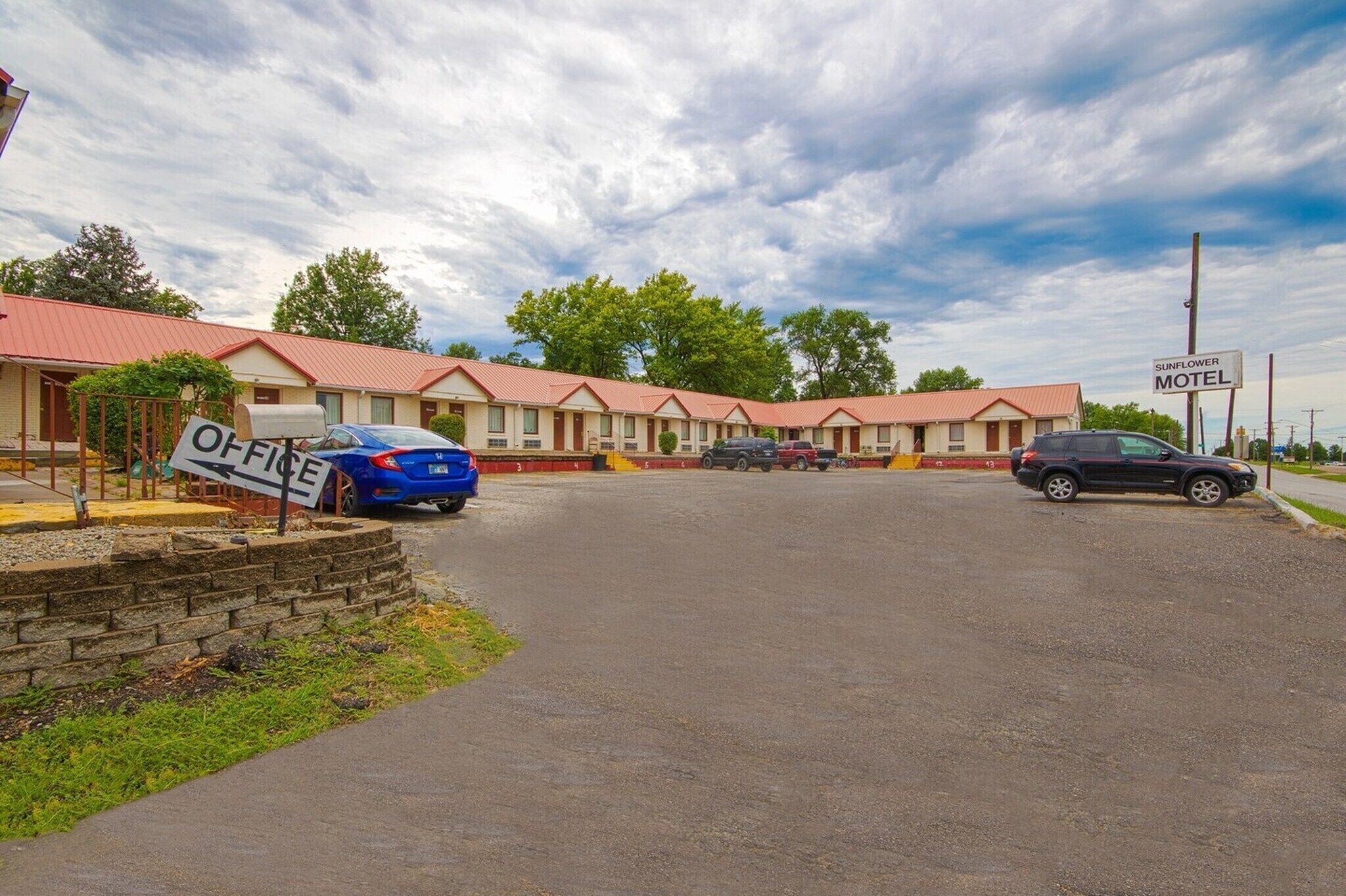 A motel with a red roof, a sign for the office, and a sign for the Sunflower Motel.