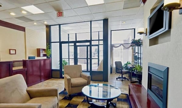 A lobby with a reception desk, seating area, and a television screen.
