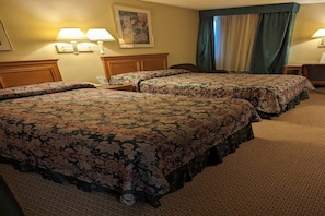 A hotel room with two beds, a desk, a chair, and a window with curtains.