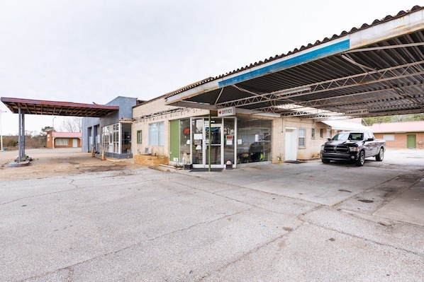 A gas station with a clear sign indicating an office, a fuel pump, and a parked vehicle.