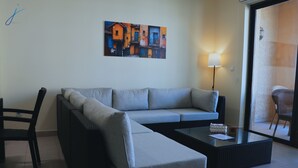 Un salon moderne avec un canapé gris, une table basse en verre et un tableau accroché au mur.