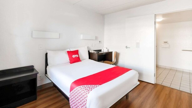 A hotel room with a bed, a desk, a chair, and a wardrobe. - King Bed | Non Smoking (Houston)