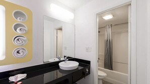 A bathroom with a black countertop, two sinks, a mirror, and a shower with a curtain. - King Bed | Non Smoking (Houston)