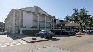 A multi-story building with a parking lot in front. - King Bed | Non Smoking (Houston)
