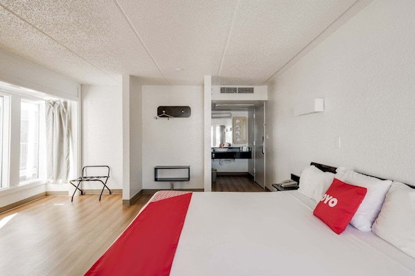 Hotellihuone, jossa on sänky, työpöytä, tuoli, televisio ja pieni keittiönurkkaus.