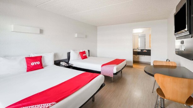 Een hotelkamer met twee bedden, een eettafel en een kitchenette.