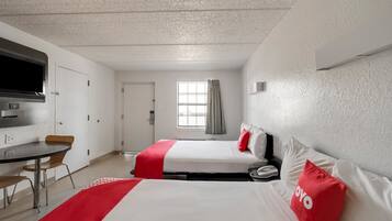 Une chambre d’hôtel avec deux lits, un bureau, une télévision et une fenêtre avec des rideaux.