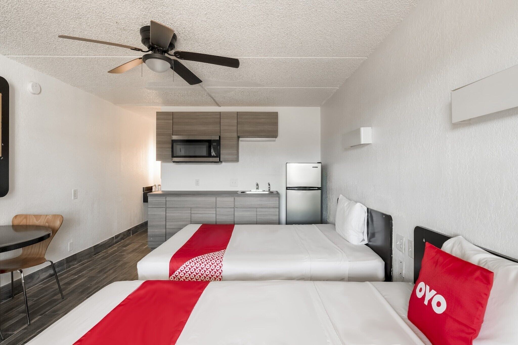 Hotelkamer met een bed, bureau, stoel, kitchenette en plafondventilator.