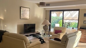 Een woonkamer met twee banken, een televisie, een lamp en een groot raam.