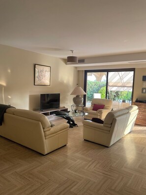 Ein Wohnzimmer mit zwei Sofas, einem Fernseher, einer Lampe und einem großen Fenster.