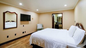 Ein Hotelzimmer mit Bett, Sessel, Fernseher und Spiegel.