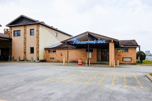 A building with a neon sign reading 'Pinewood Inn' and a parking lot in front. - OYO Pinewood Inn & Suites Silsbee|King Bed (Houston)