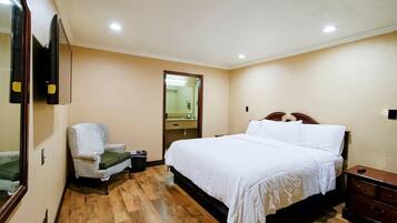 Un dormitorio con cama, una silla, cómoda y espejo.