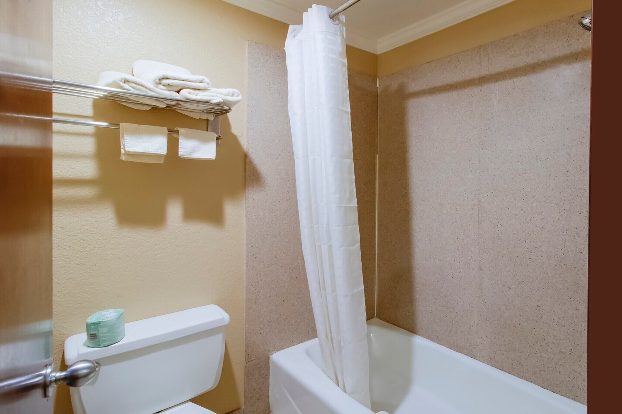 Un baño con bañera, inodoro y toallero con toallas dobladas.