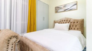 A bedroom with a bed, a wardrobe, a chair, and a painting on the wall. - Cozy Studio apartment with AC in tranquil Nairobi (Nairobi)
