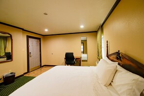 Ein Hotelzimmer mit Bett, Schreibtisch, Stuhl, Spiegel und Tür.
