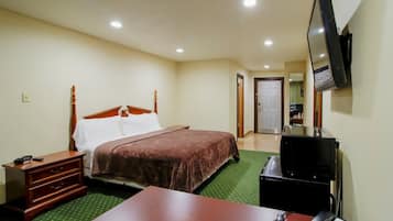 Une chambre d’hôtel comprenant un lit, un bureau avec un téléphone, un téléviseur fixé au mur et un miroir.