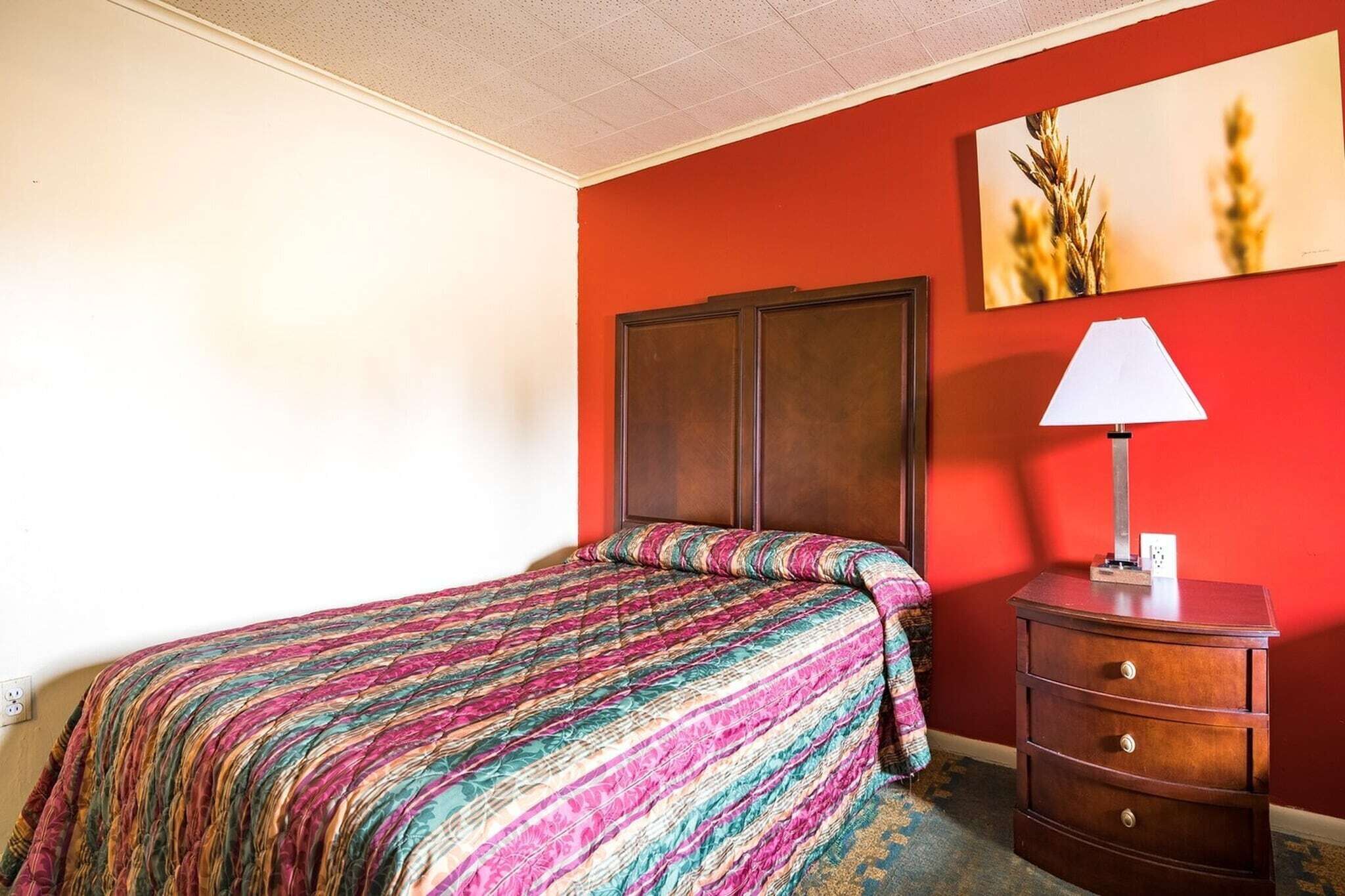 Una habitación con una cama, un tocador y un cuadro en la pared.