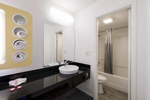 Ein Badezimmer mit schwarzem Waschtisch, zwei Waschbecken, einem Spiegel und einer Duschkabine mit Vorhang.