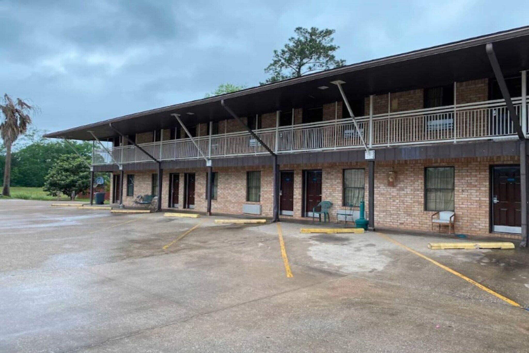 A two-story motel with a covered parking area and a brick facade.