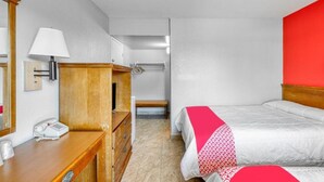 Une chambre d’hôtel comprenant un lit, une table de chevet avec une lampe, une commode en bois et un miroir.