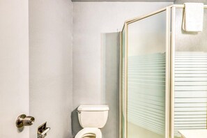 Une salle de bain comprenant des toilettes, une douche avec une porte en verre et une serviette accrochée à la porte de la douche.