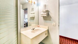 Une salle de bain avec un lavabo, un miroir, un porte-serviettes et une porte.