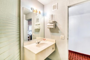 A bathroom with a sink, mirror, towel rack, and a door. - Houston | 2 Full Bed (Houston)
