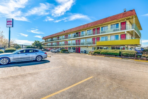 A multi-story motel with a red roof, balconies, and a sign indicating it is an OVO hotel. - Houston | 2 Full Bed (Houston)