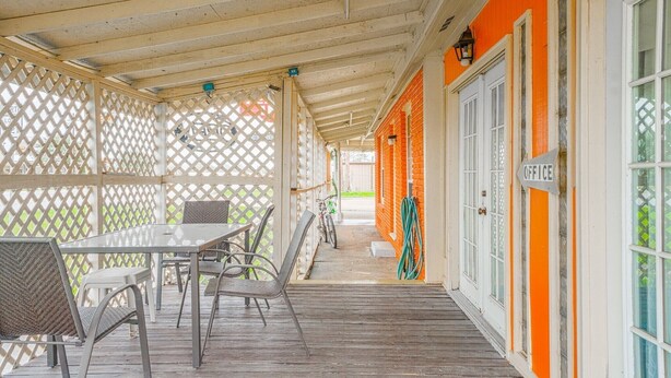 A covered outdoor seating area with a table and chairs, a bicycle, and a hose.