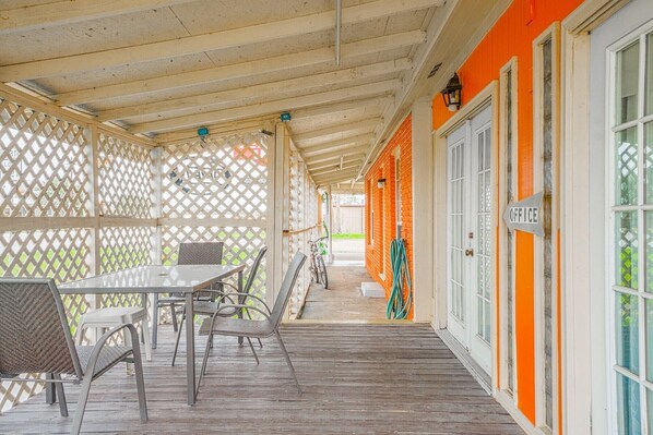 A covered outdoor seating area with a table and chairs, a bicycle, and a hose.